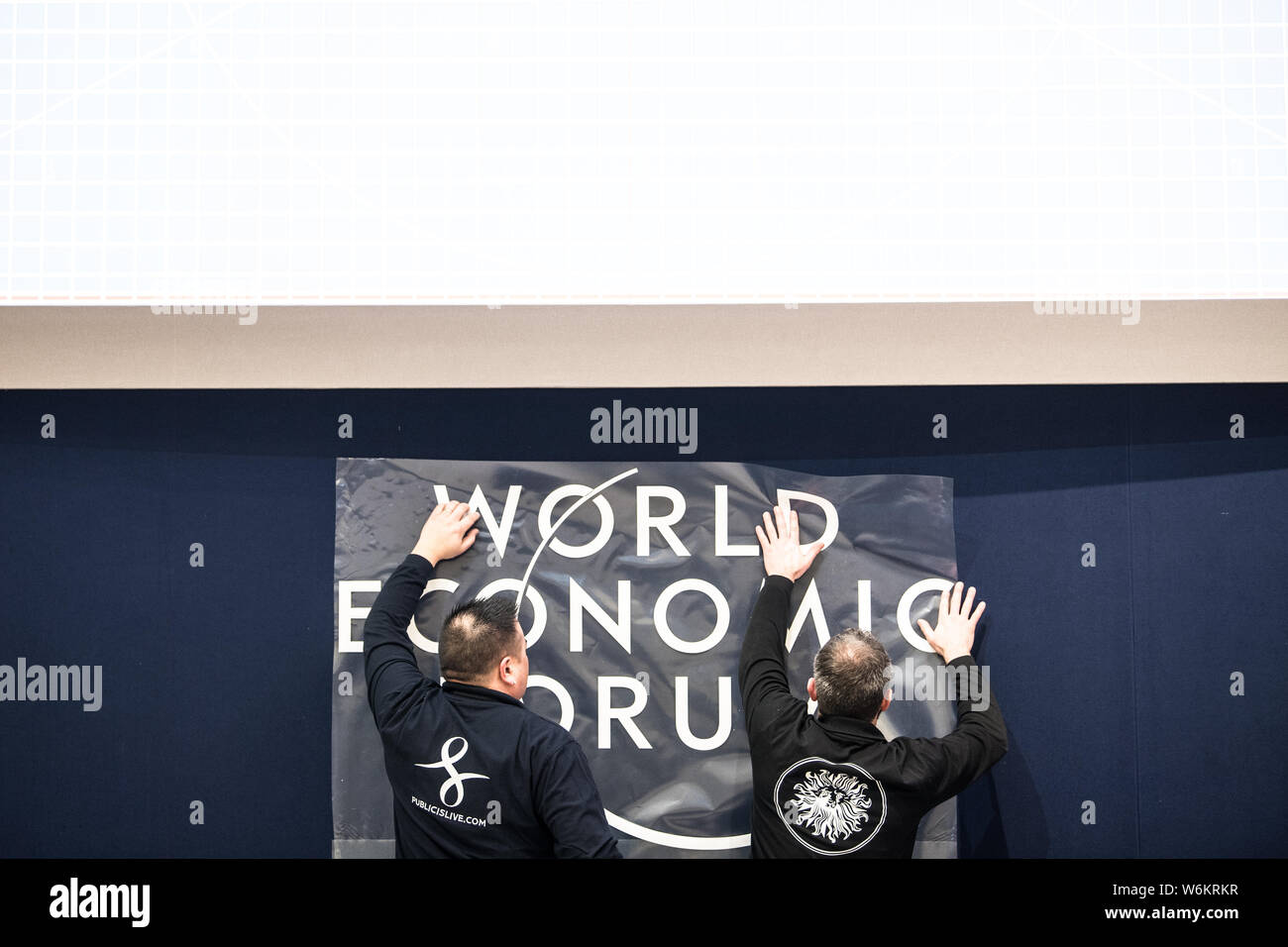 Workers paste a logo of World Economic Forum Annual Meeting ahead of the 48th World Economic Forum (WEF) Annual Meeting in Davos, Switzerland, 20 Janu Stock Photo
