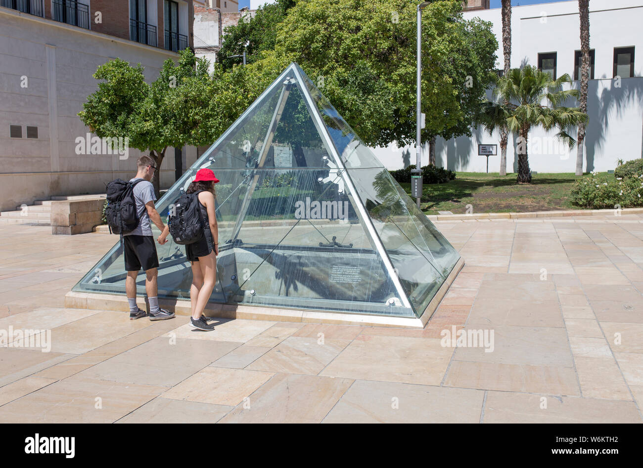 Young couple of visitors observing roman ruins through glass pyramid at ...