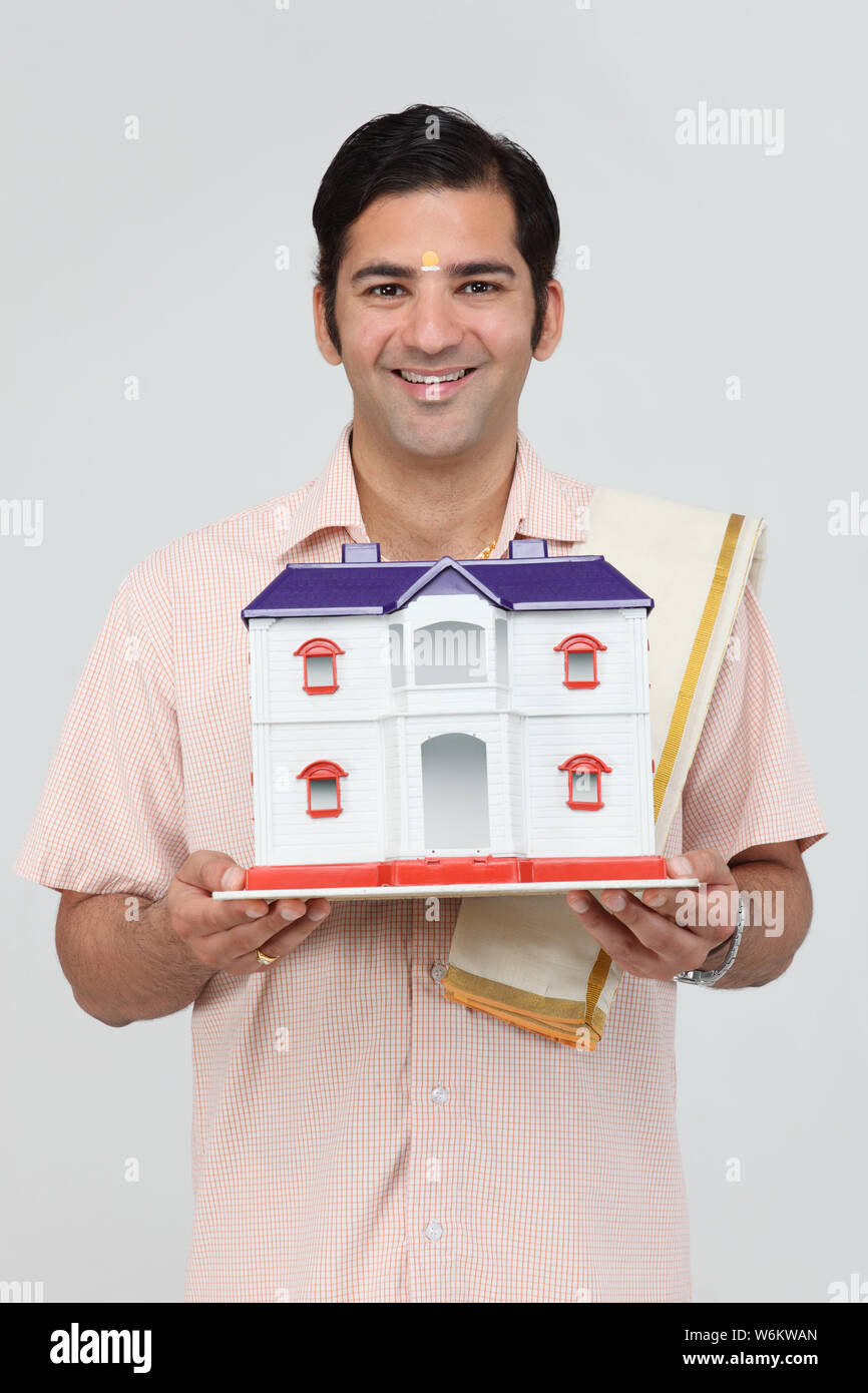 South Indian man holding a model of dream home and smiling Stock Photo ...