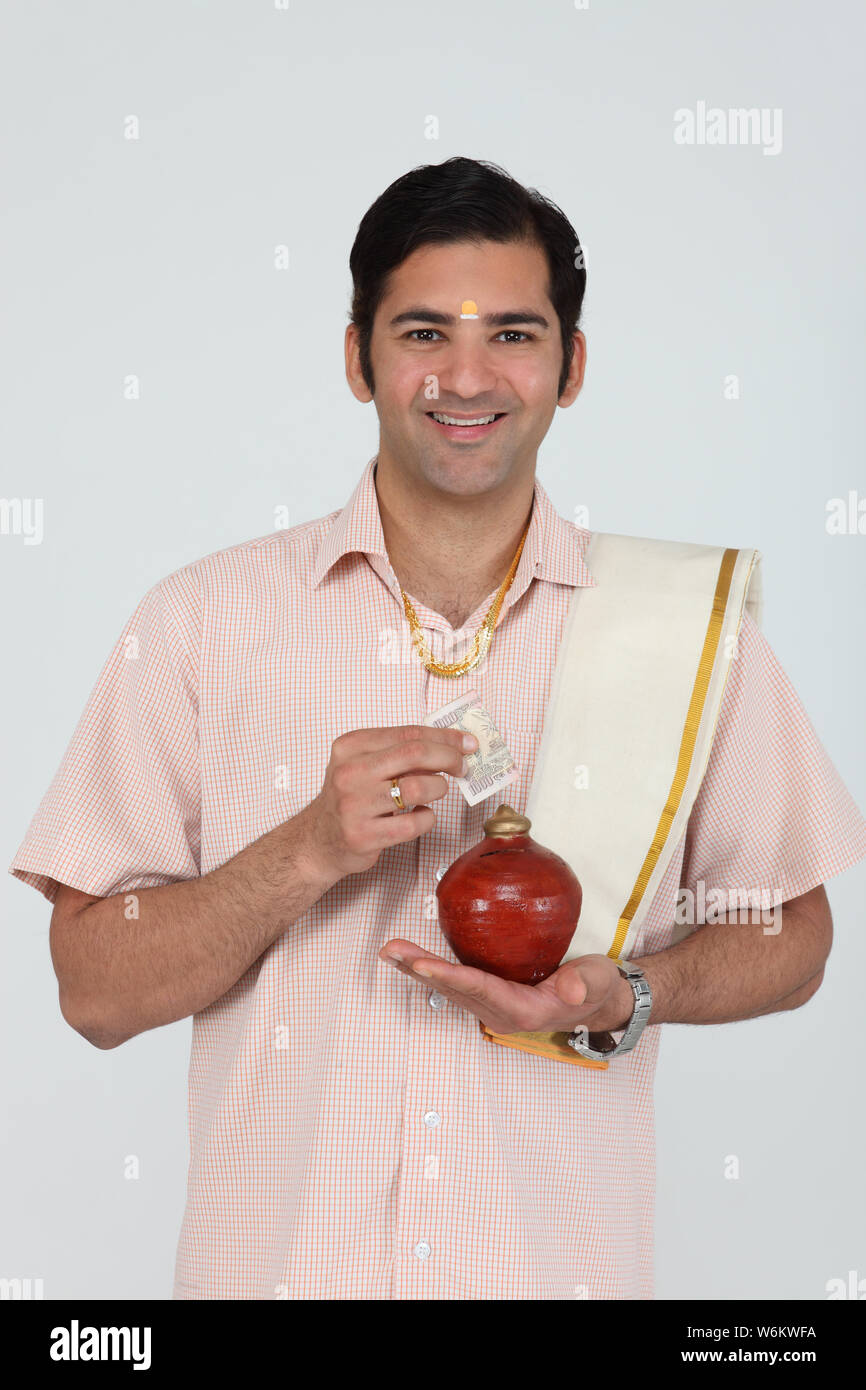 South Indian man putting banknote into a piggy bank Stock Photo - Alamy
