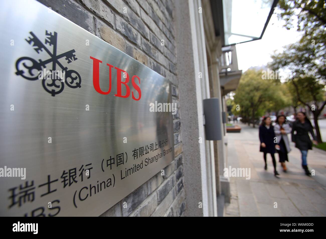 --FILE--Pedestrians walk past a logo of Zurich-based financial services provider UBS Group in Shanghai, China, 24 March 2016.   Zurich-based financial Stock Photo
