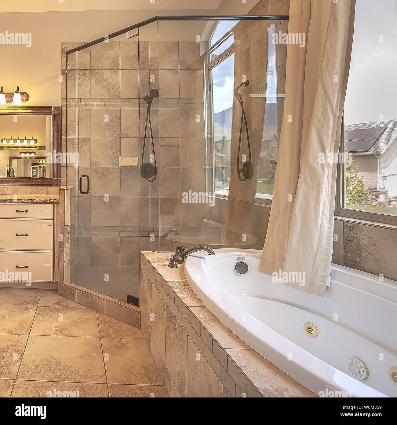 Square frame Shower stall beside an oval bathtub in front of an arched