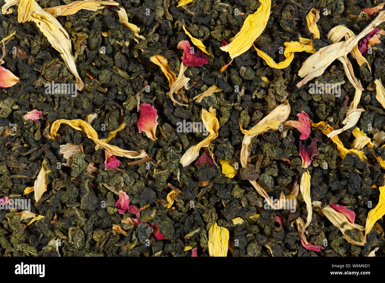 Green tea loose dried tea leaves and sunflower petals close-up Stock