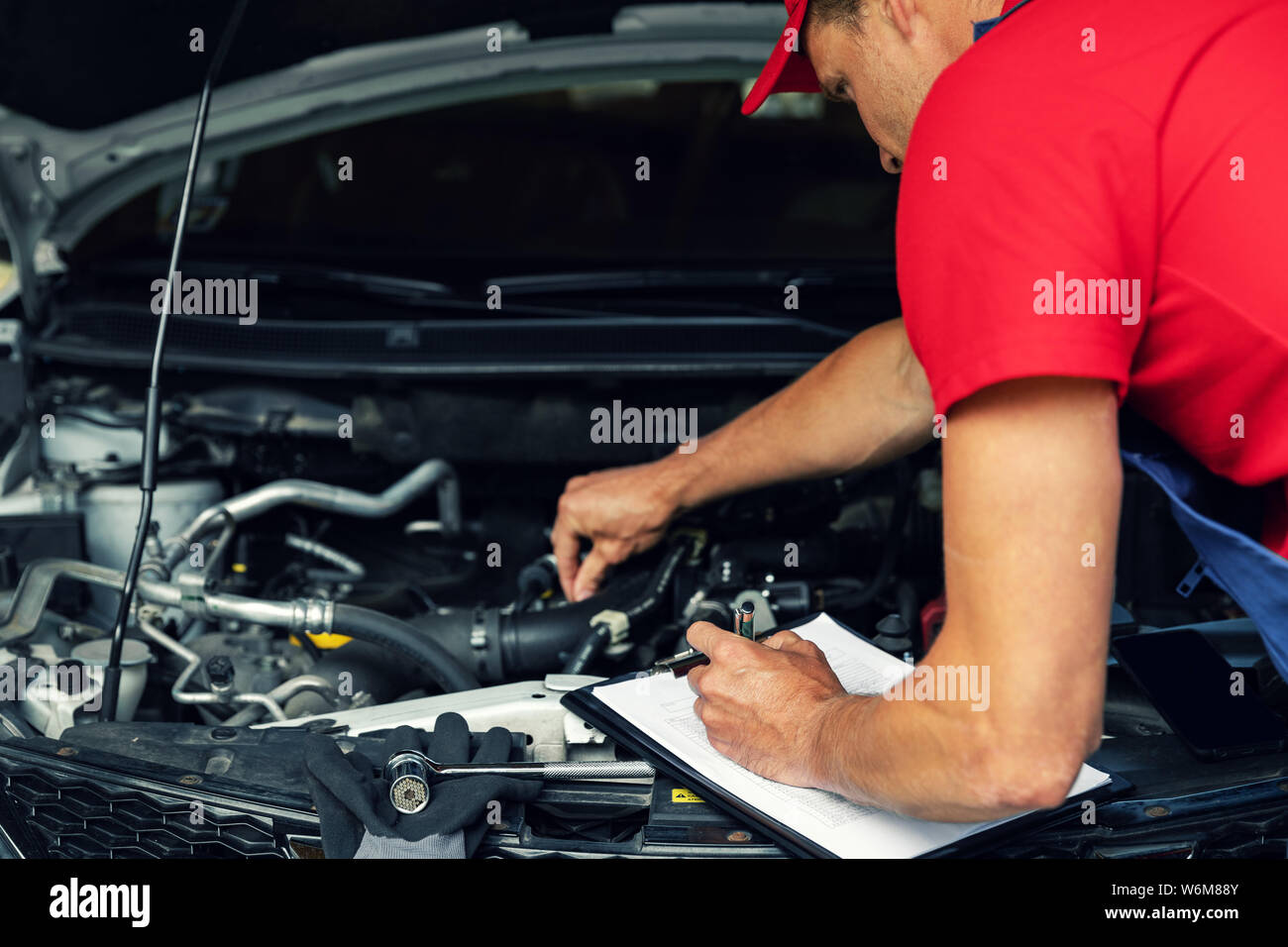 car maintenance - mechanic check the engine and writing in checklist Stock Photo