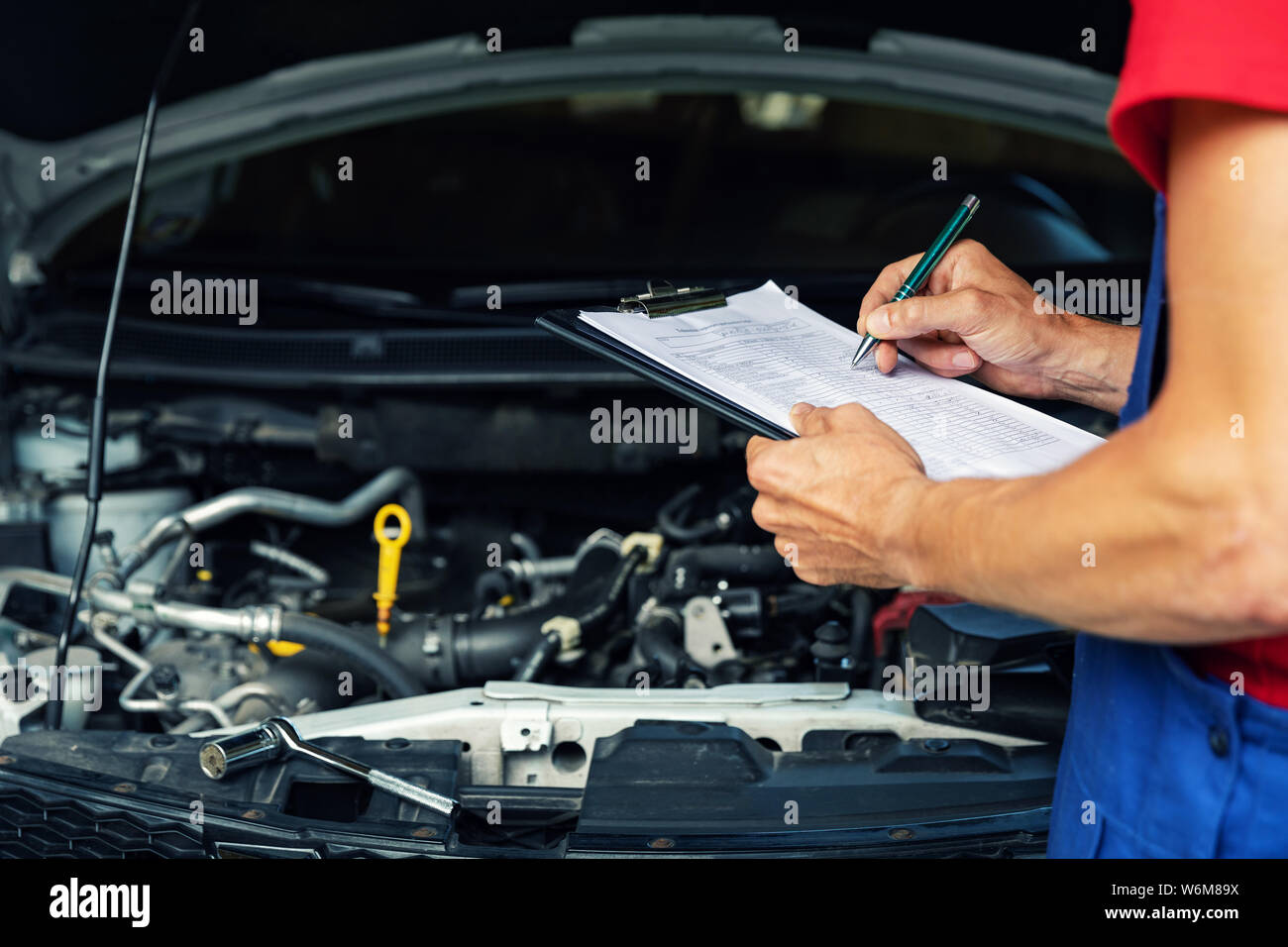 car maintenance and repair - mechanic writing checklist paper on