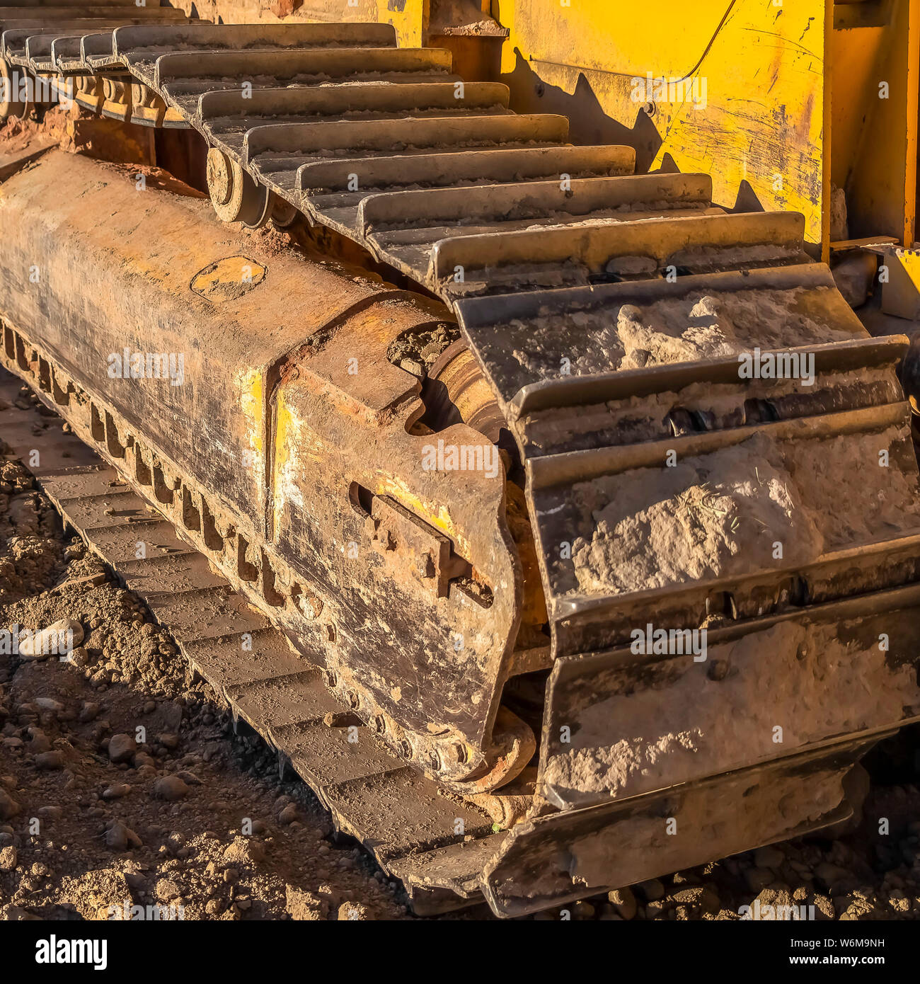 Square frame Dirty metal track pad of a yellow construction machinery on a sunny day. Stock Photo