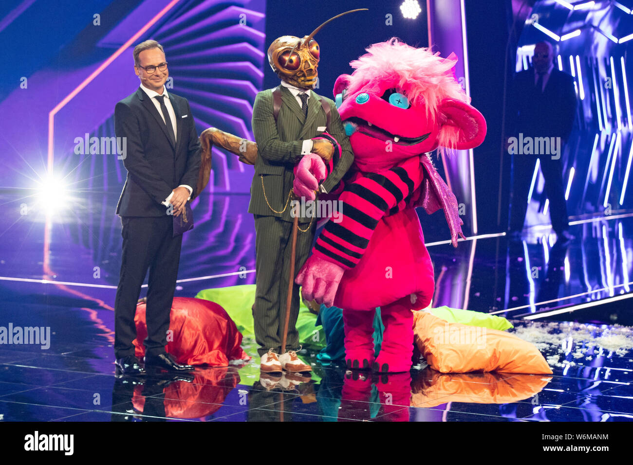 Cologne, Germany. 01st Aug, 2019. The boxer Susianna Kentikian (r) is the  "monster" at the ProSieben show "The Masked Singer" on stage next to the  character "Grashüpfer" (M) and presenter Matthias Opdenhövel (
