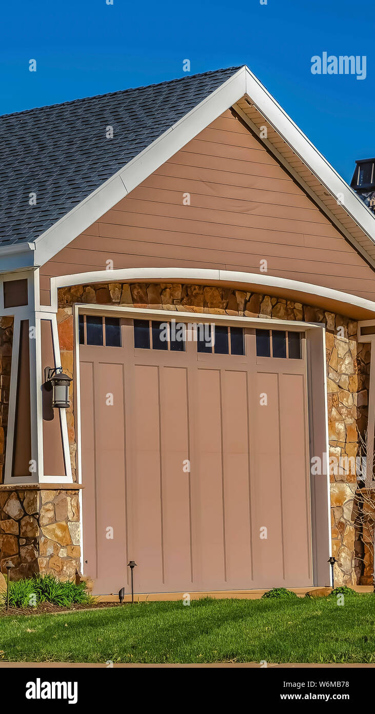 Vertical Frame Home With Garage Door Front Lawn And Metal Gate