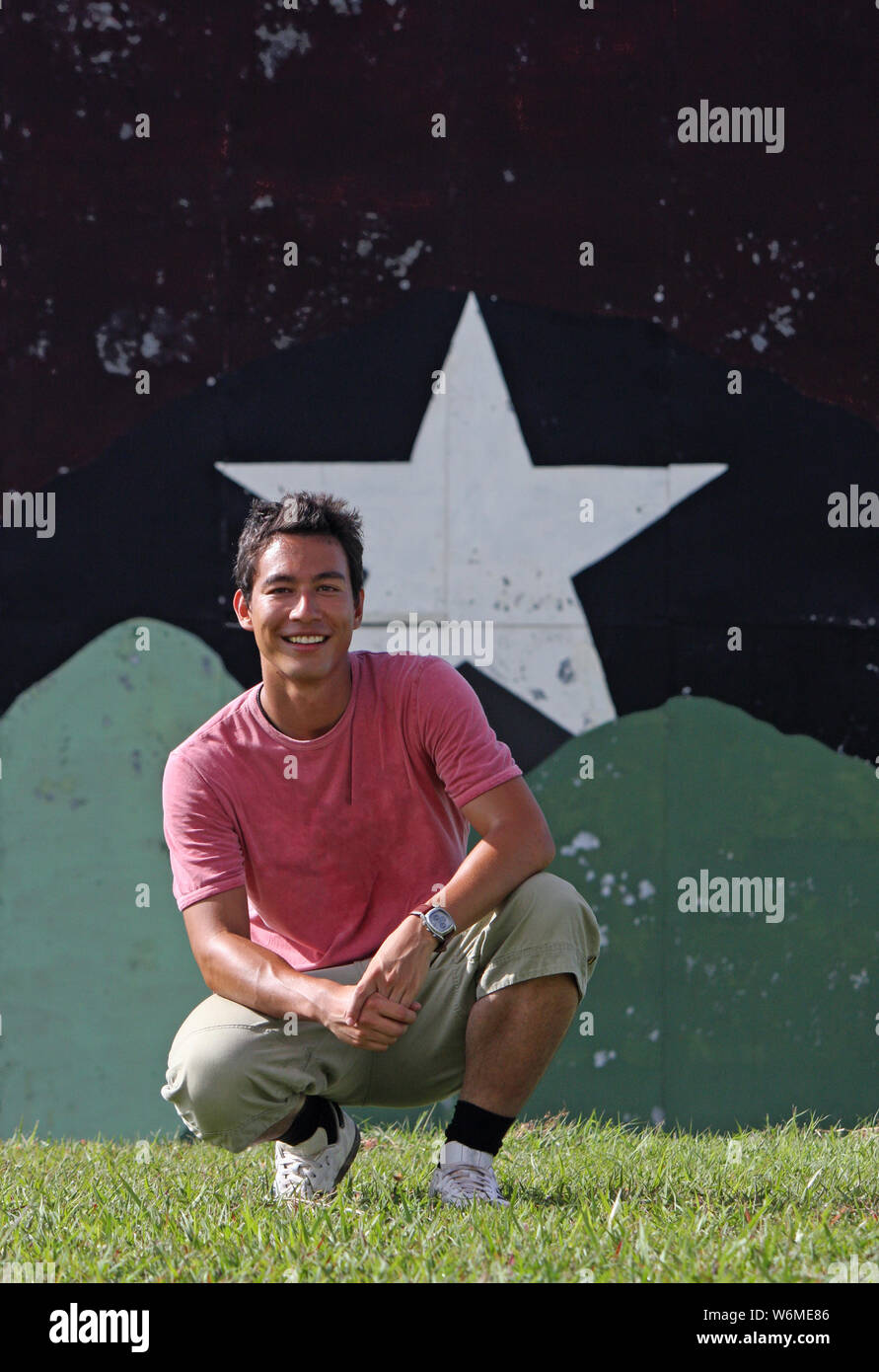 Young man sitting in front of a background with a big star painted on it Stock Photo