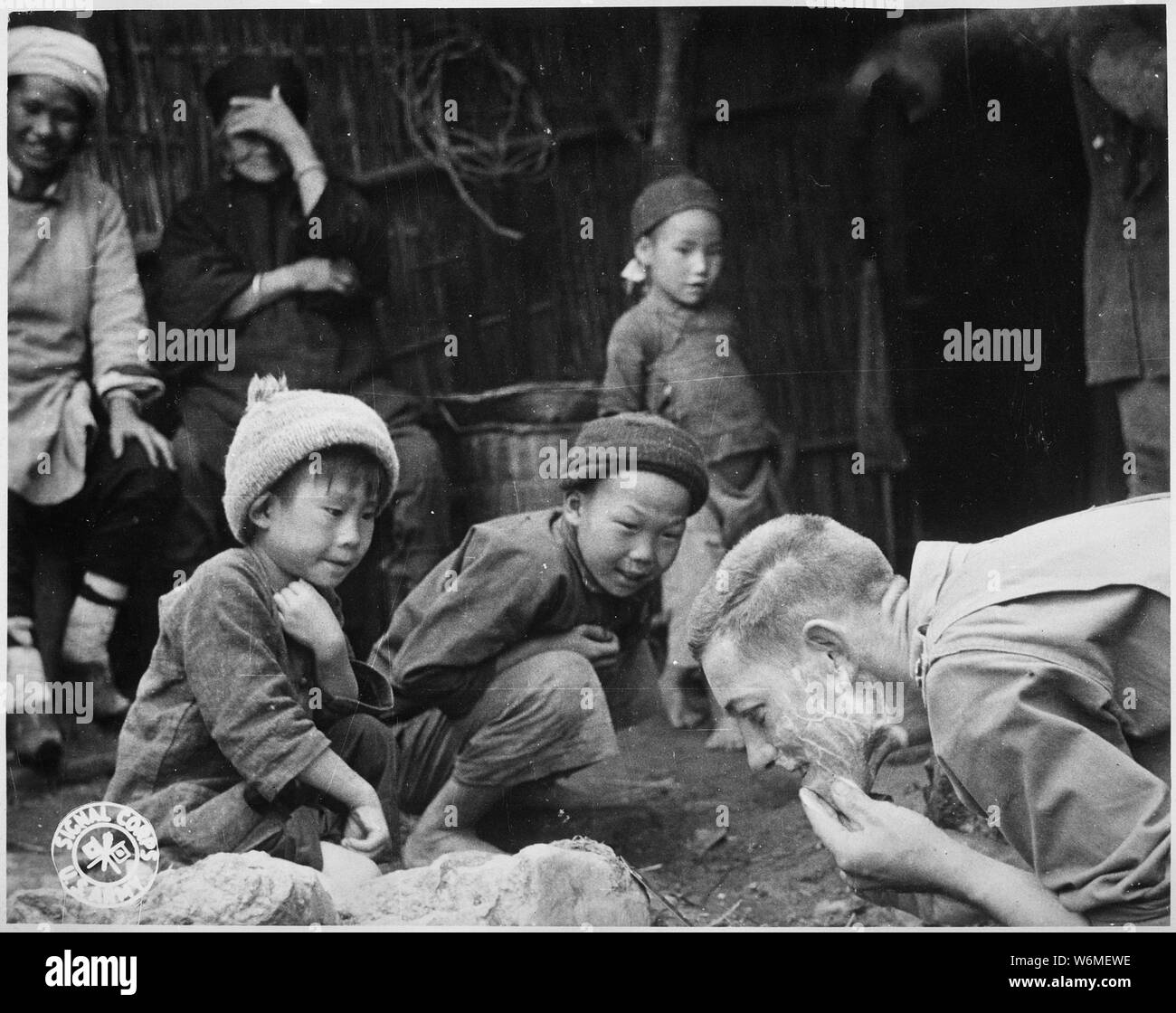 These two Chinese youngsters are fascinated by the sight of an American soldier shaving in the open. Yunnan, China.; General notes:  Use War and Conflict Number 1265 when ordering a reproduction or requesting information about this image. Stock Photo