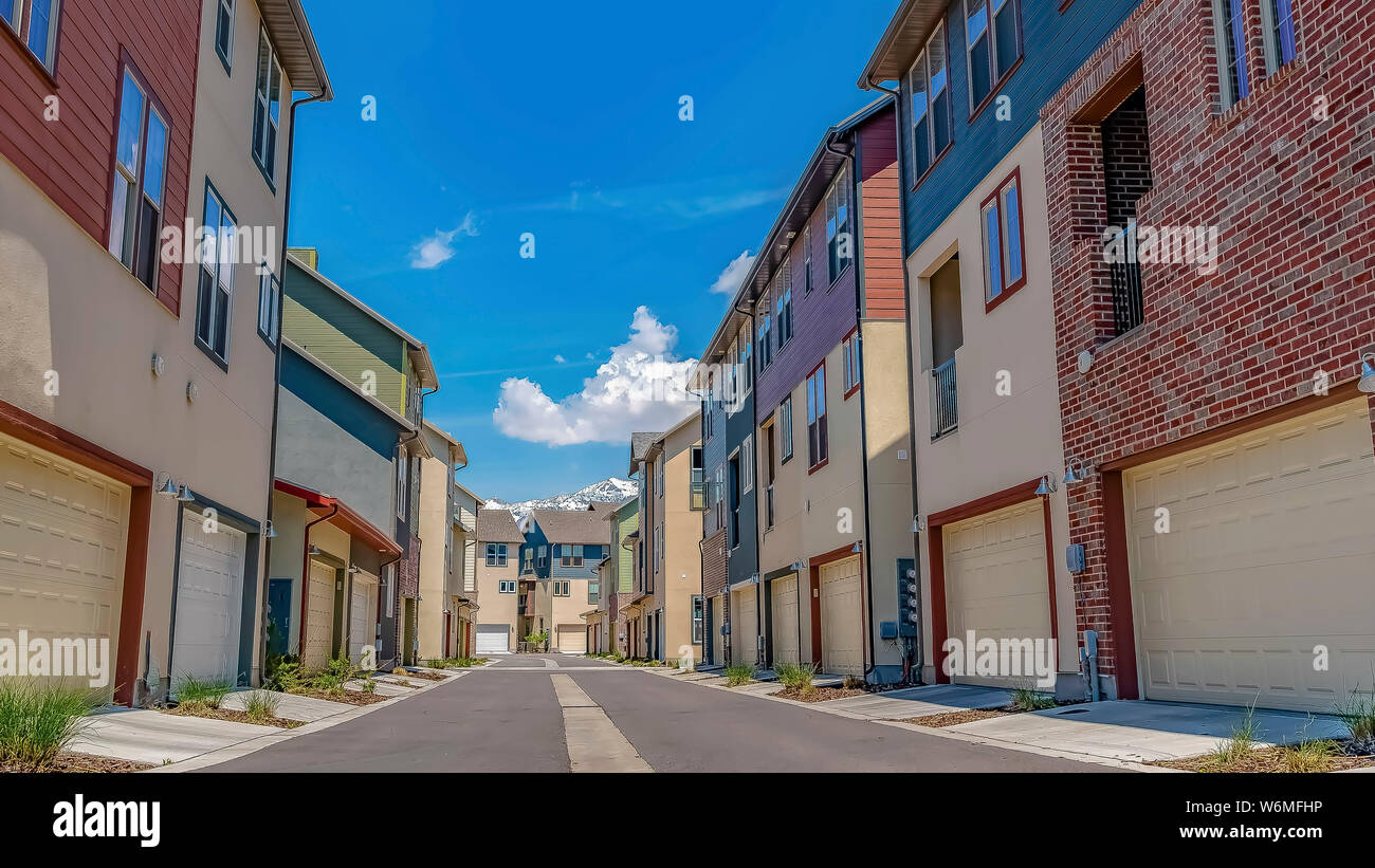 Panorama frame Rows of houses with paved road in the middle under blue ...