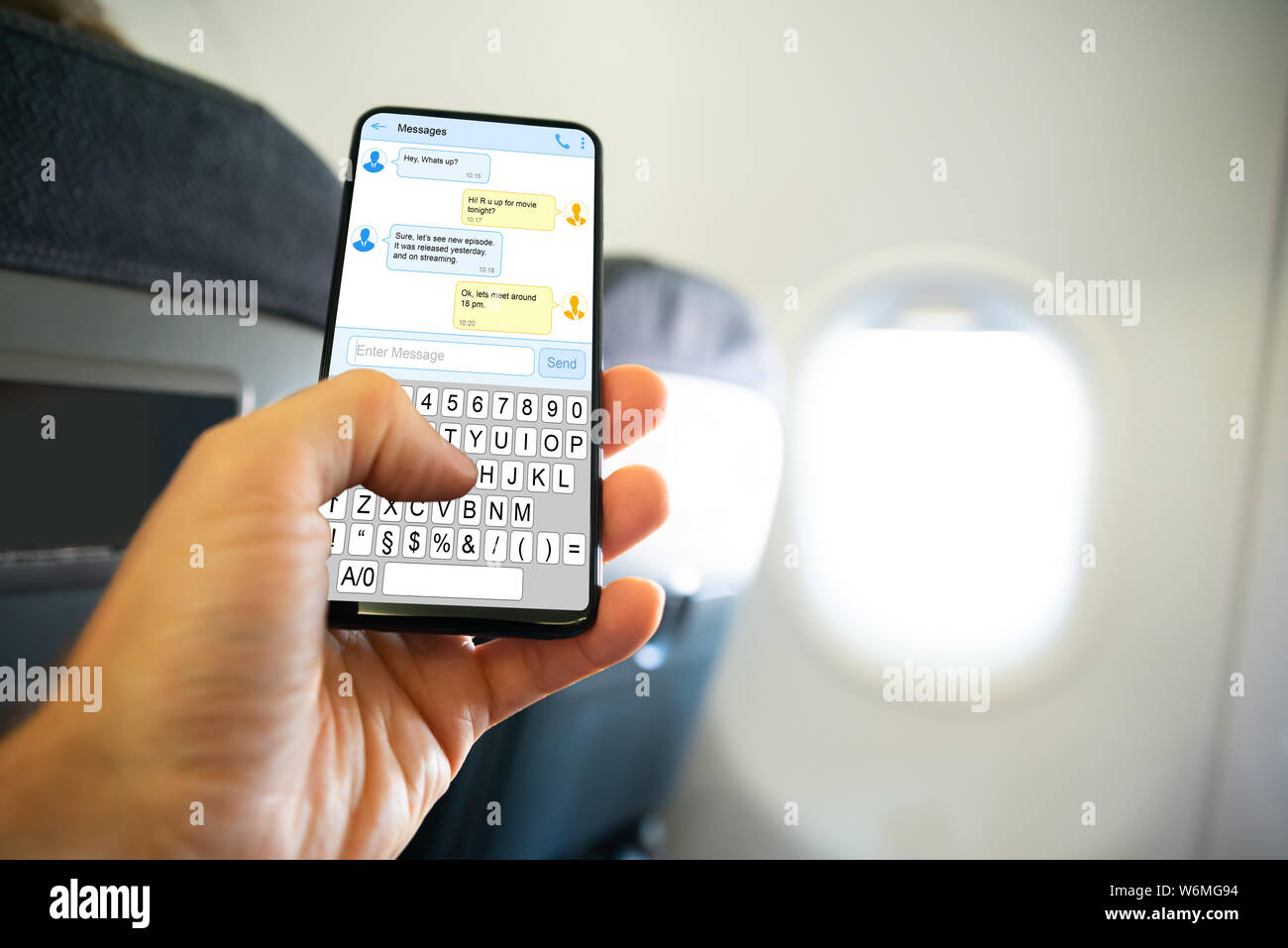 Close-up Of Person's Hand Writing SMS Message On Mobile Phone On Airplane Stock Photo