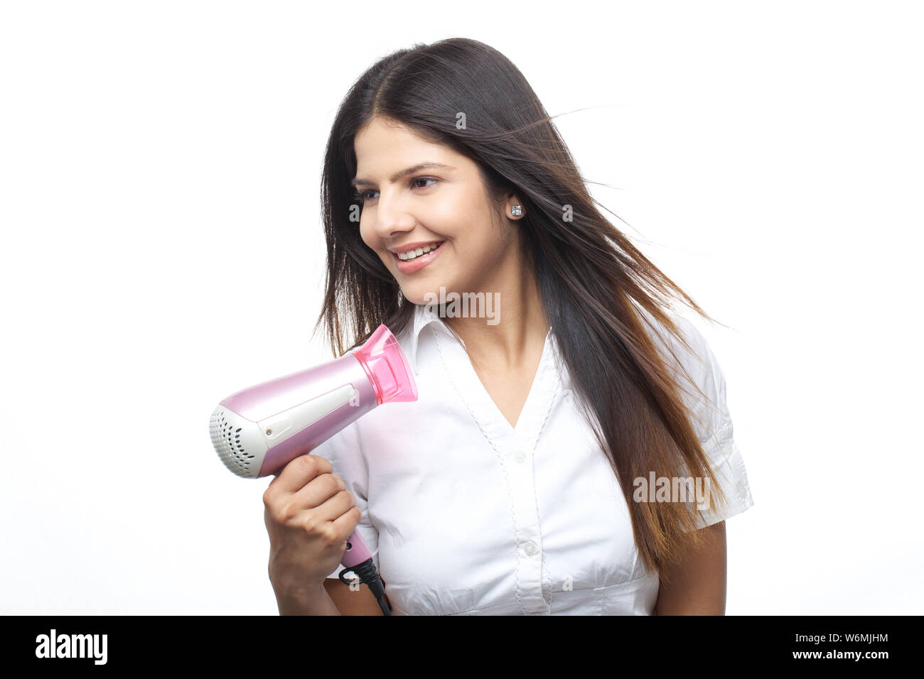 Young woman blow drying her hair and smiling Stock Photo - Alamy