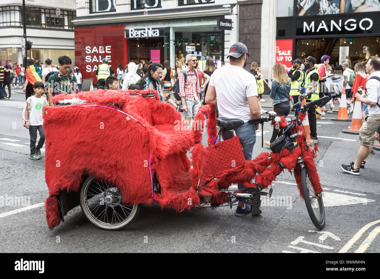 Rickshaw London. Pedicab London. Oxford Street London UK: people shopping and red tuk tuk. Stock Photo
