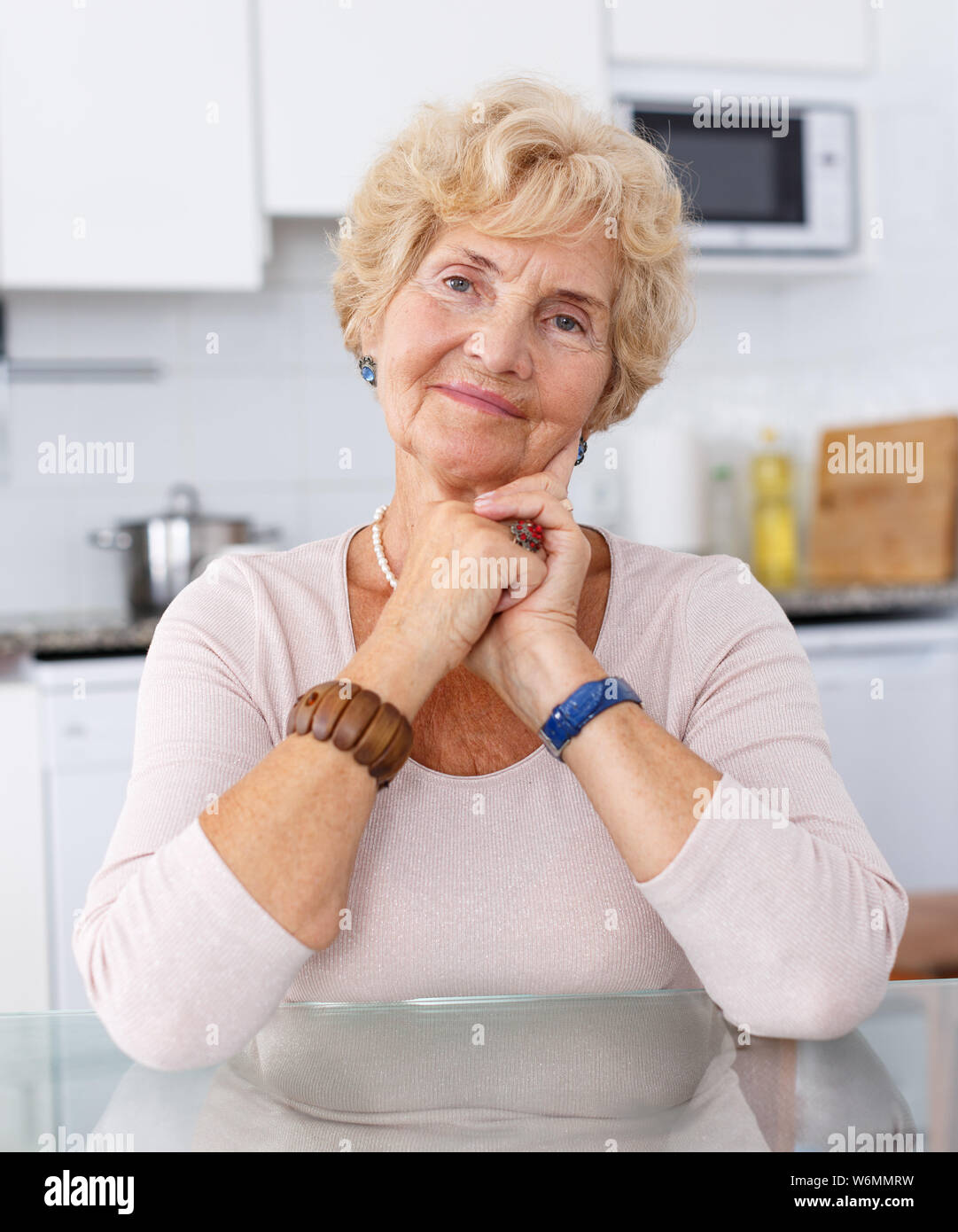 Portrait of attractive senior woman sitting at kitchen table Stock Photo