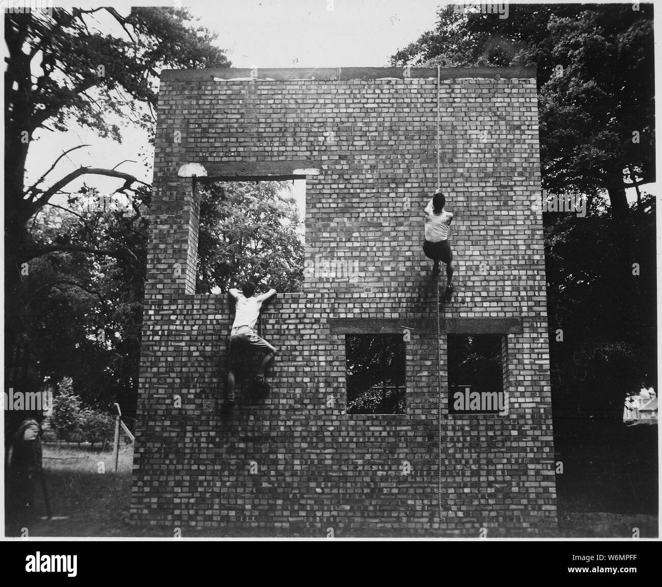 Two Jeds scale brick wall in training exercises. Milton Hall, England, circa 1944., 1943 - 1944; General notes:  Use War and Conflict Number 736 when ordering a reproduction or requesting information about this image. Stock Photo