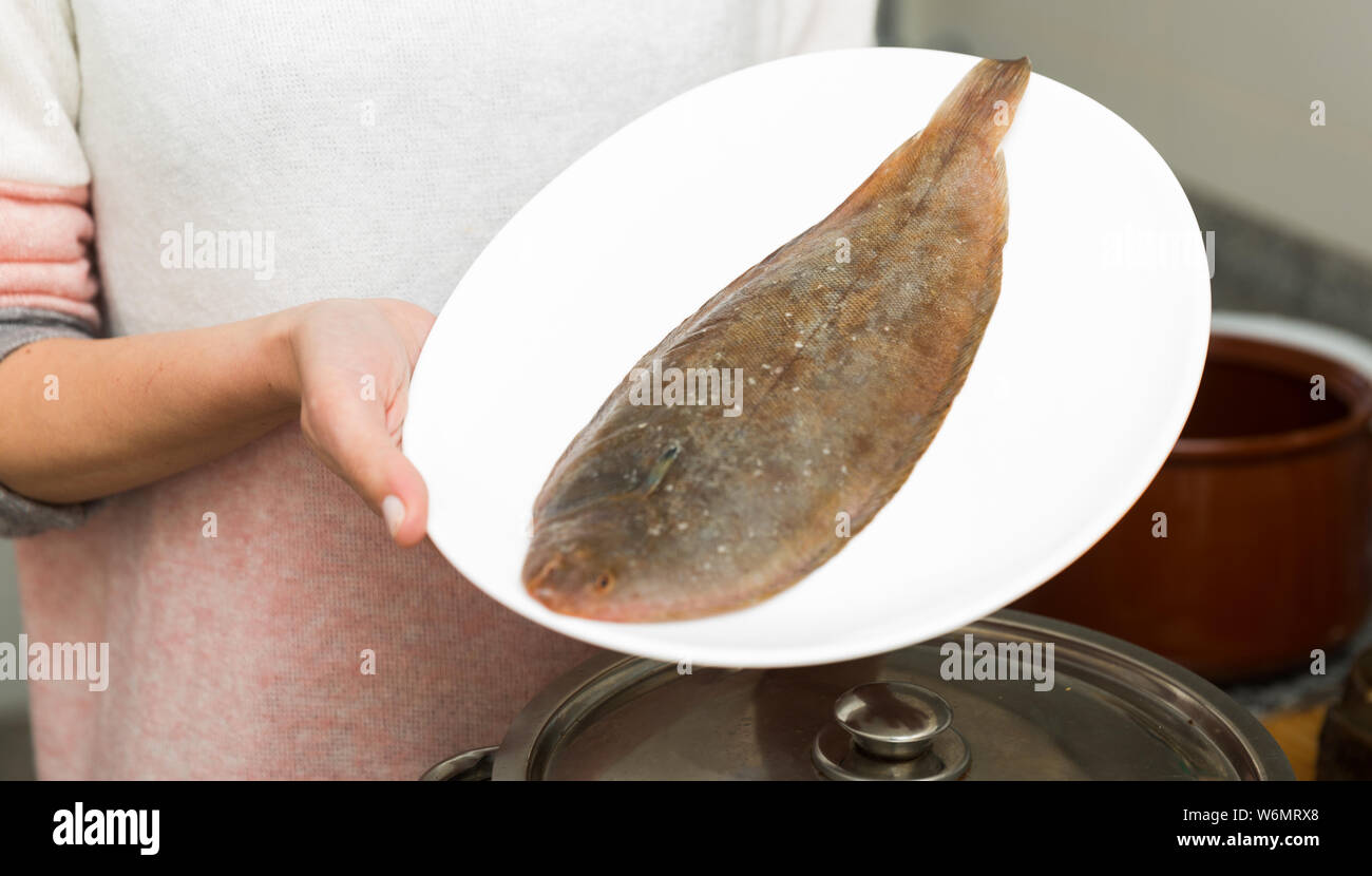 Closeup of raw common sole on white plate in female hands Stock Photo