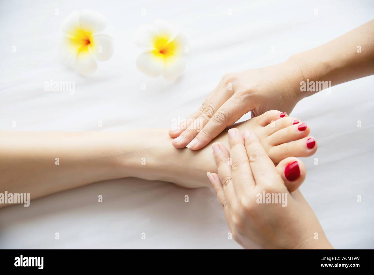 Woman receiving foot massage service from masseuse close up at hand and foot - relax in foot massage therapy service concept Stock Photo