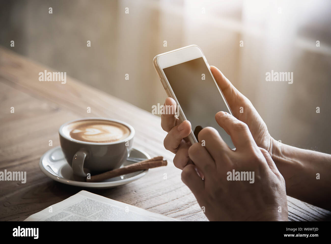 Man using mobile phone while drinking coffee and reading book in coffee shop - modern life style people in coffee shop concept Stock Photo