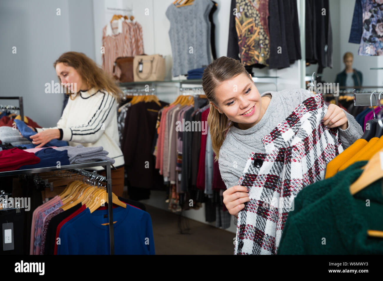 Shopping room of clothing shop with women choosing overcoats and cardigans Stock Photo