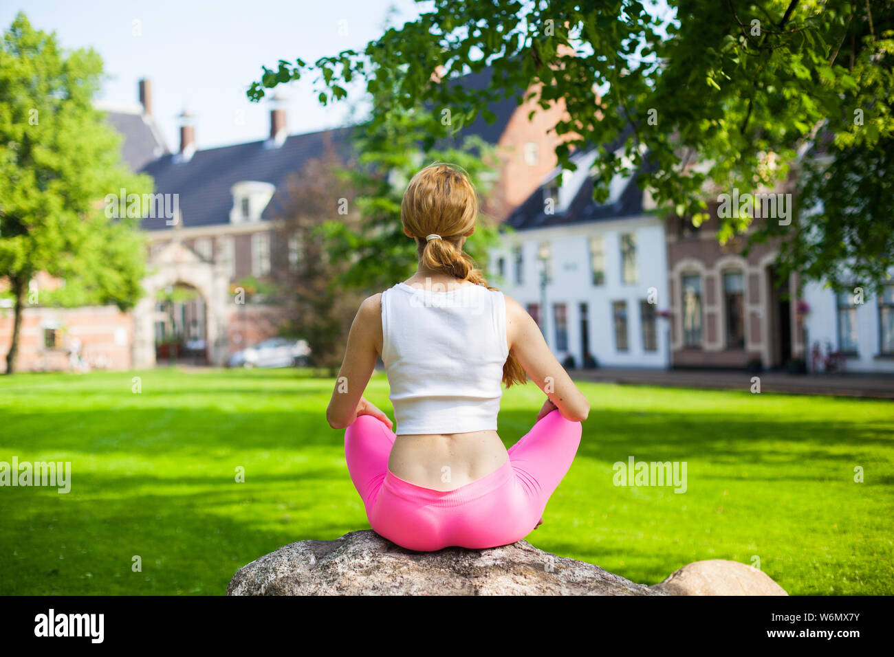 Blonde young woman in morning city park. woman with long blond hair meditating and  doing yoga exercisers in city street, healthy lifestyle concept Stock Photo