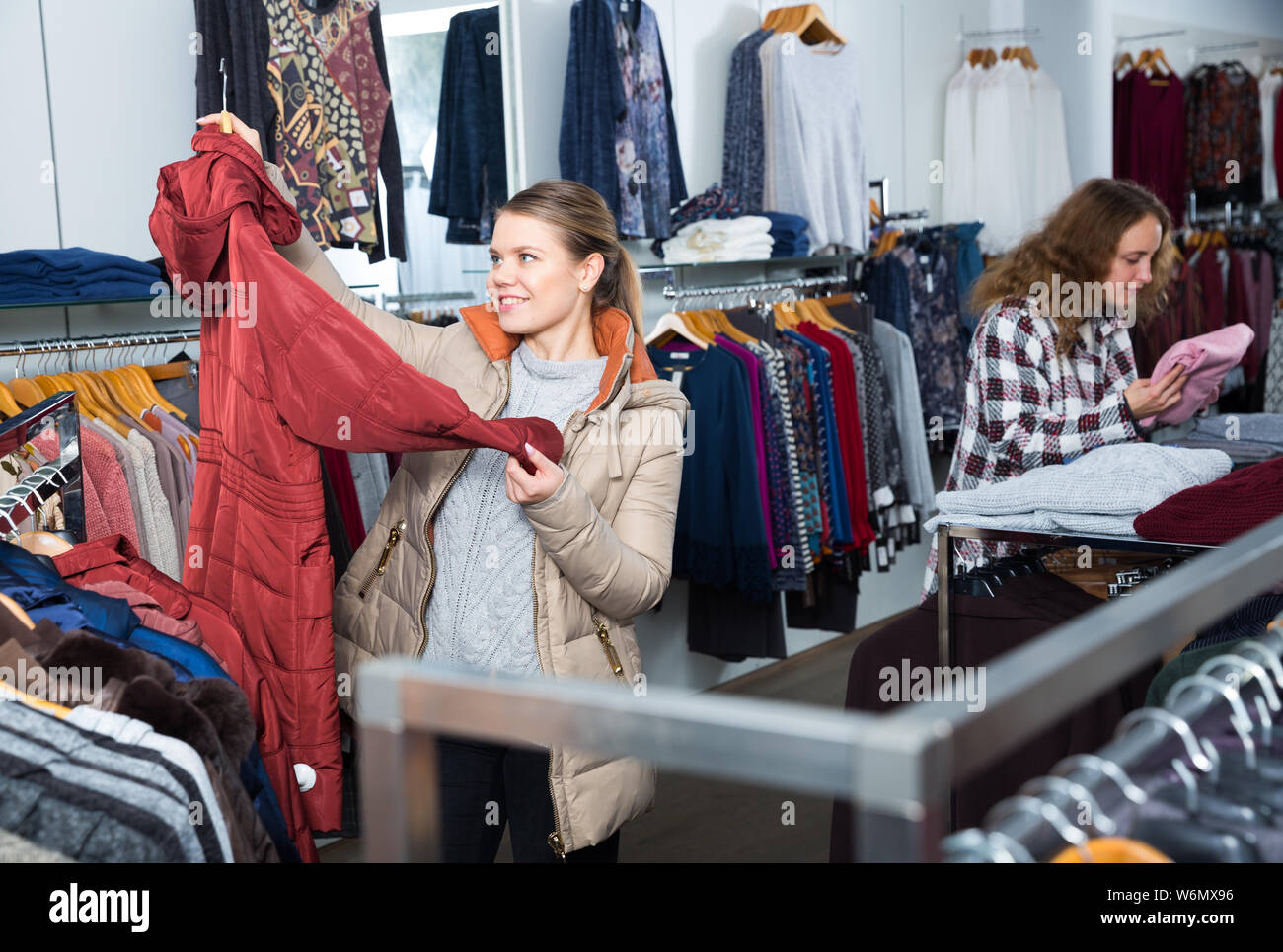 Shopping room of clothing shop with women choosing overcoats and cardigans Stock Photo