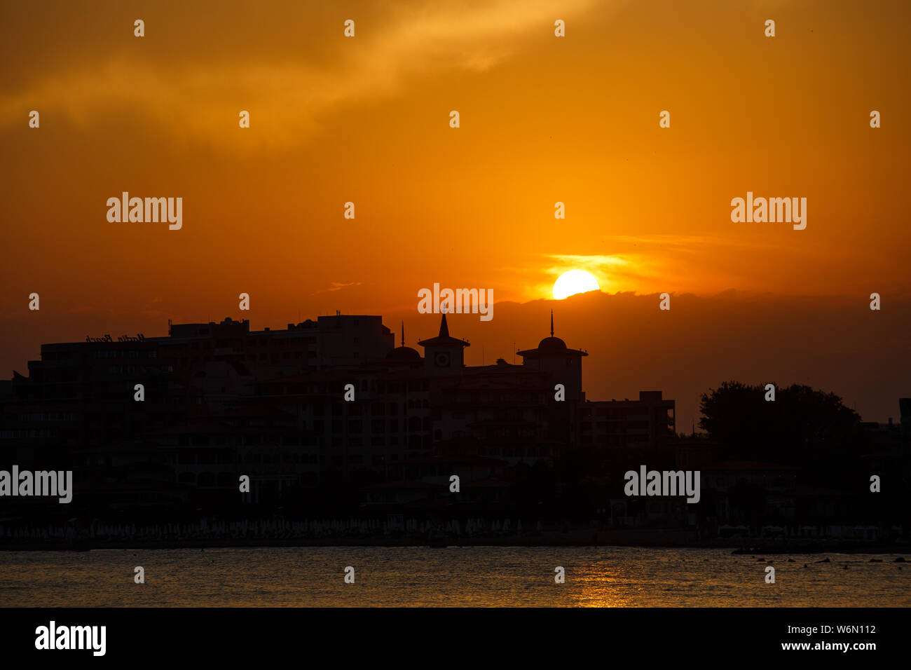 Golden sunset on the beach. Silhouette of the city. Beautiful architecort by the sea on the background of the sunset. Stock Photo