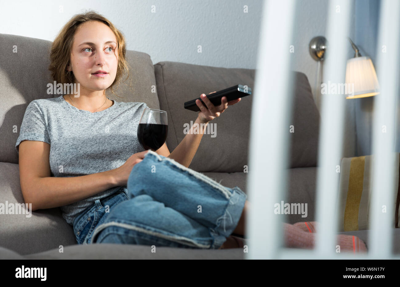 Young woman relaxing with glass of wine and watching TV at home Stock ...