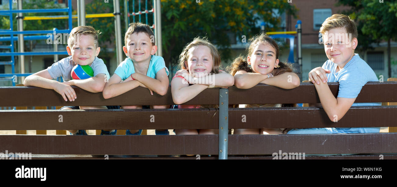 Glad children sitting on a bench at the playground Stock Photo - Alamy