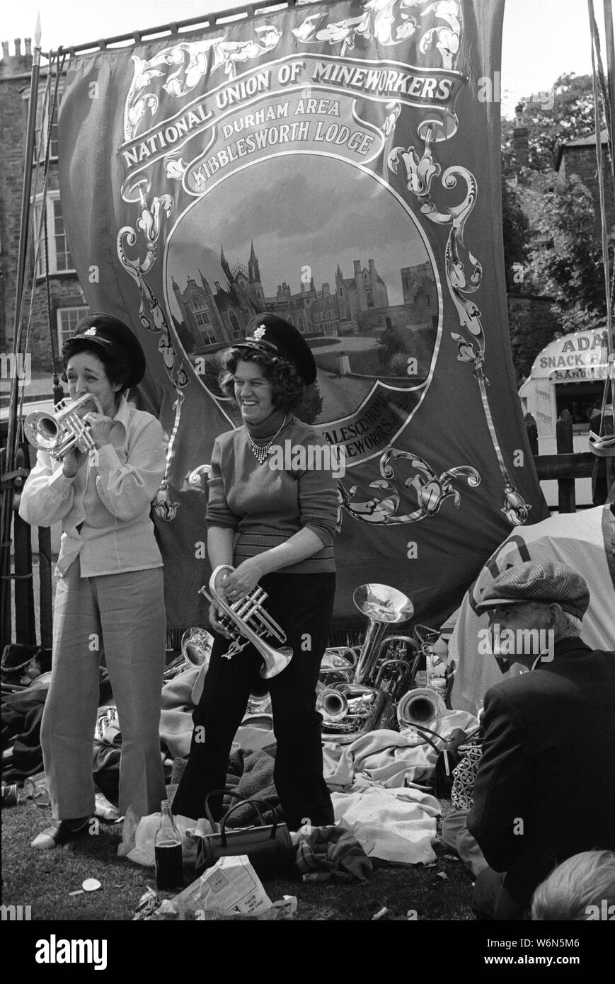 Durham Miners Gala. Two coal miners wives, are having fun and playing on the colliery silver bands musical instruments under the National Union of Mineworkers, Durham area Kibblesworth Lodge banner 70s County Durham, England UK 1970s.  HOMER SYKES Stock Photo