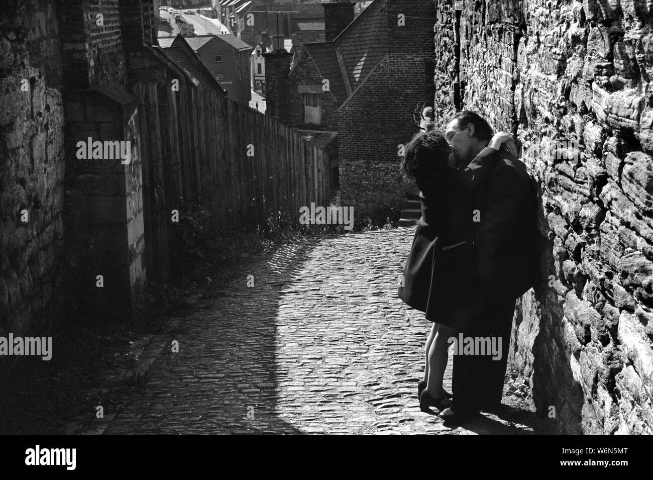 Couple kissing, 1970s older elderly seniors embrace, lovers being passionate in a back alley in a Durham, County Durham 1974 UK 70s HOMER SYKES Stock Photo