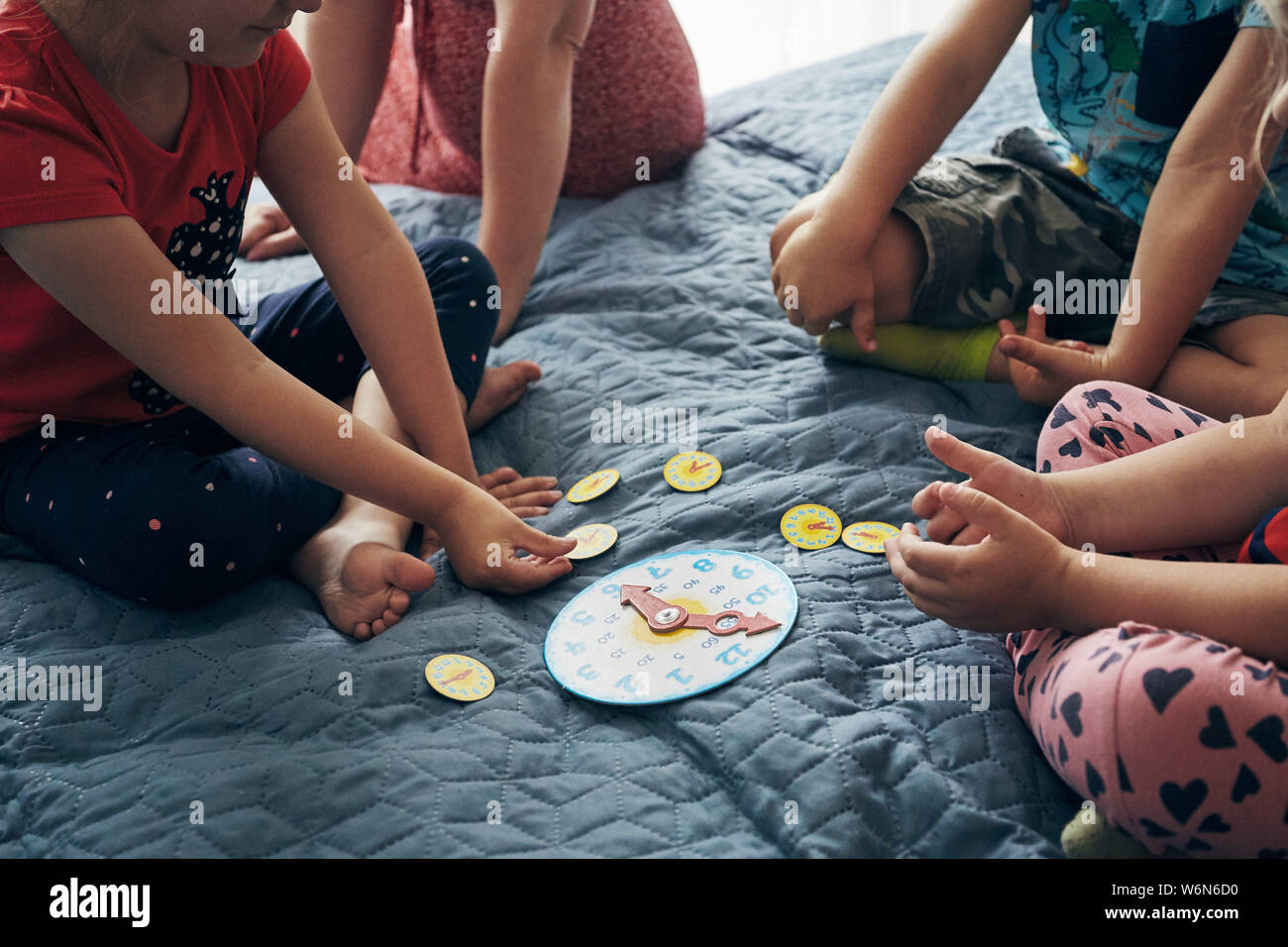 Kids learning how to tell time from clock and set the hands in the correct position. Teaching preschoolers tell time. Candid people, real moments, aut Stock Photo