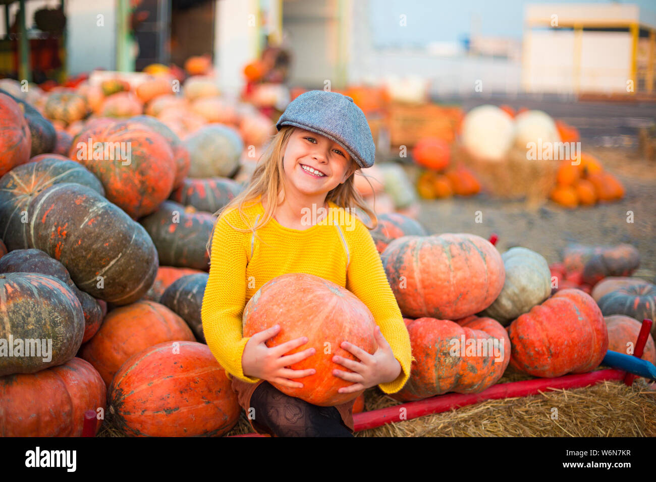 Happy little girl at the autumn pumpkin patch background. Having fun ...