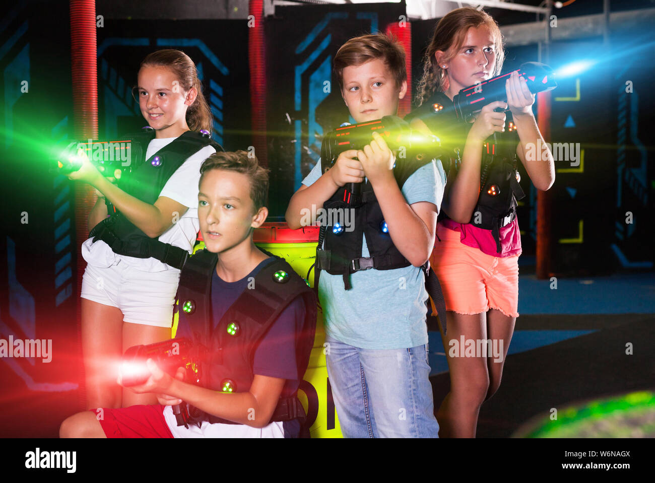 Cheerful teen girls and boys with laser pistols posing together in dark  laser tag labyrinth Stock Photo - Alamy