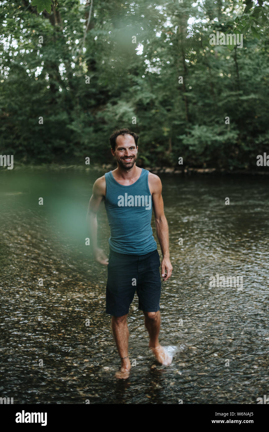 happy man wading through the water of a river Stock Photo