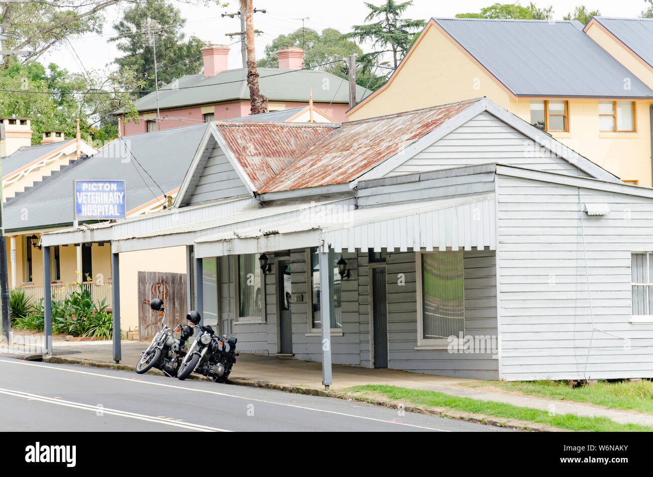 Two motorbikes parked outside a simple former workers cottage now housing the Picton Veterinary Hospital at 199 Menangle St, Picton NSW 2571 Stock Photo