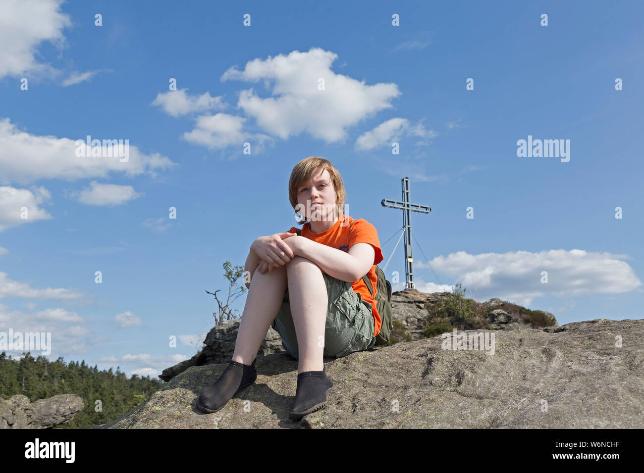 boy with minimalist shoes sitting on the summit of Rauchröhren (smoke tubes), Eck, Bavarian Forest, Bavaria, Germany Stock Photo