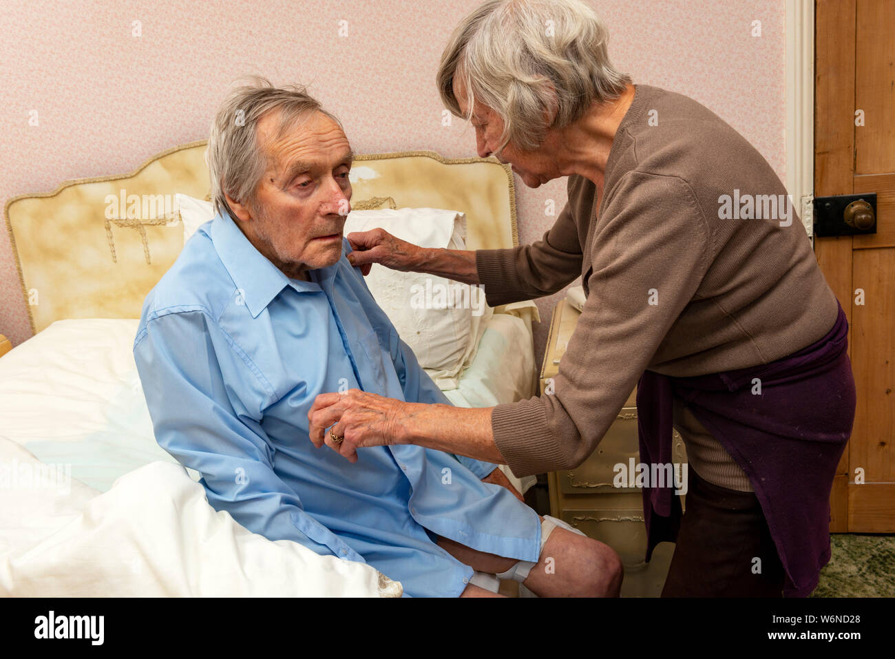 Elderly man being helped to get dressed hires stock photography and