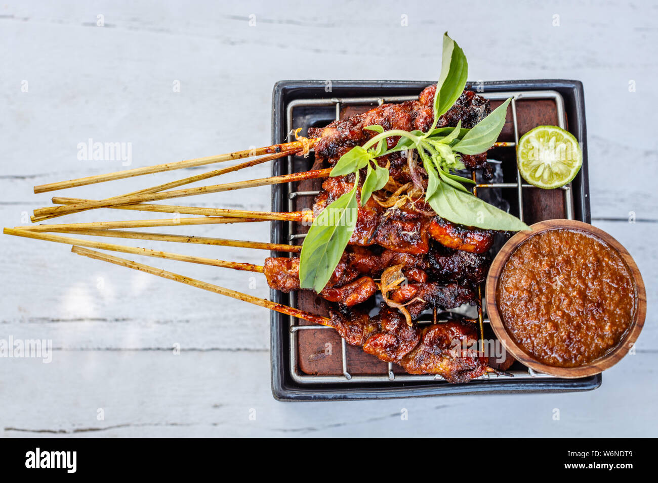 Sate ayam (chicken sate, grilled meat on bamboo skewers), traditional Indonesian dish, served with sambal kacang, peanut sauce. Bali, Indonesia. Stock Photo