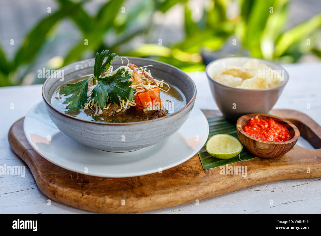 Sop Buntut, oxtail soup with potato, carrot and been sprouts. Served with spicy sambal sauce and potato chips. Traditional Indonesian cuisine. Stock Photo