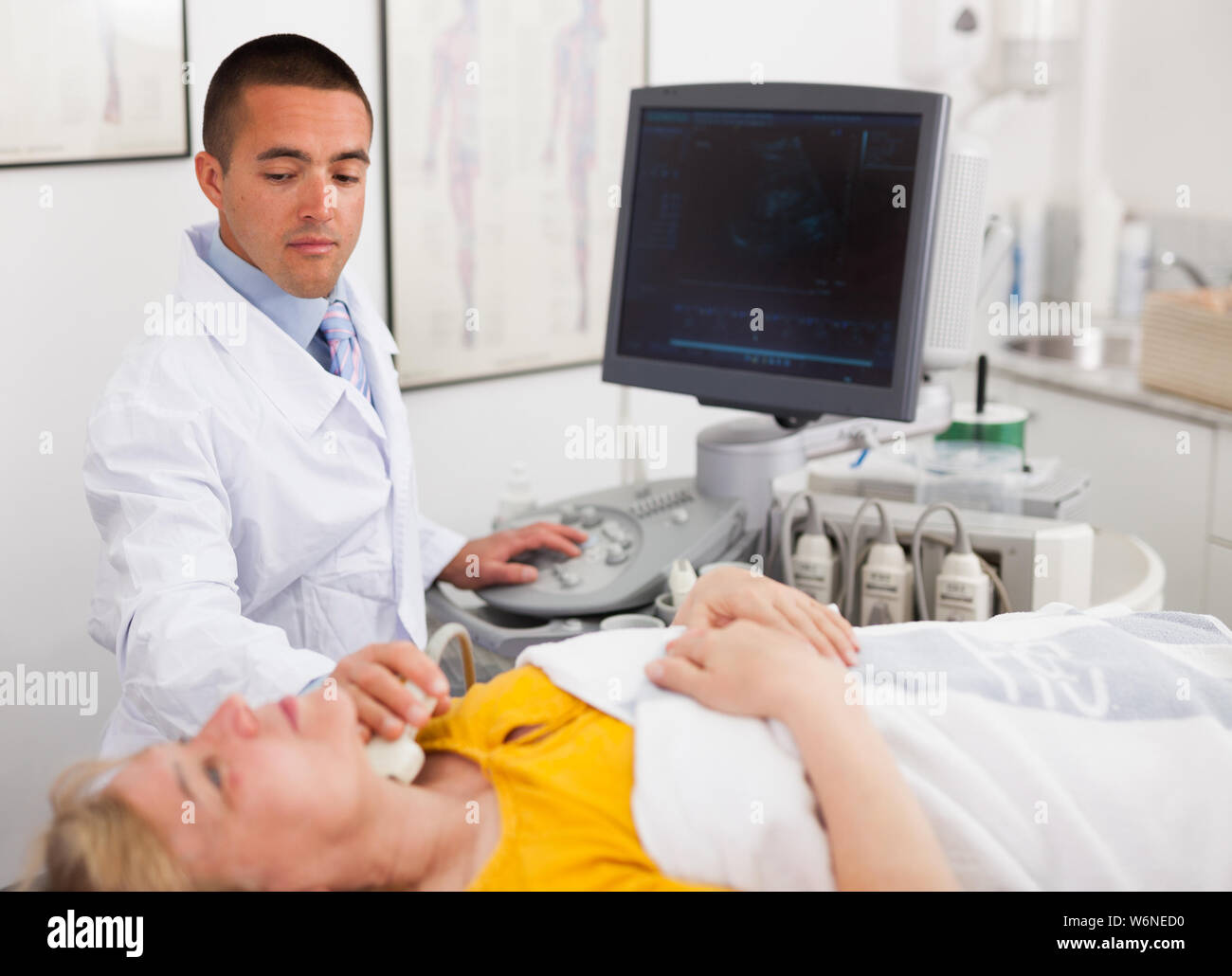 Positive male doctor diagnosing female patient using modern ultrasound ...