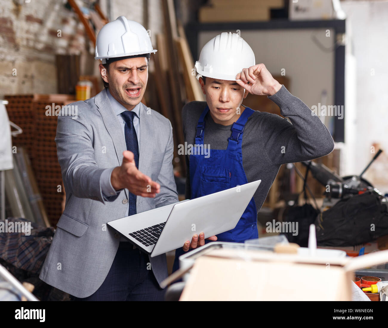 Angry male manager unhappy with quality of work of employee on building ...