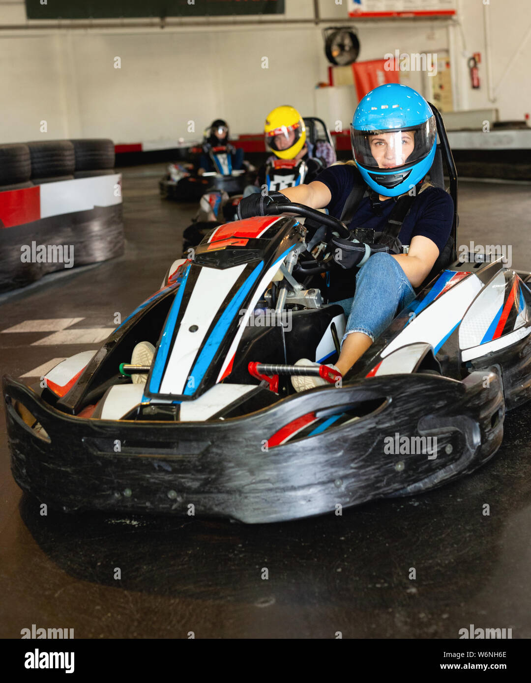 Glad positive smiling girl and her friends competing on racing cars at ...