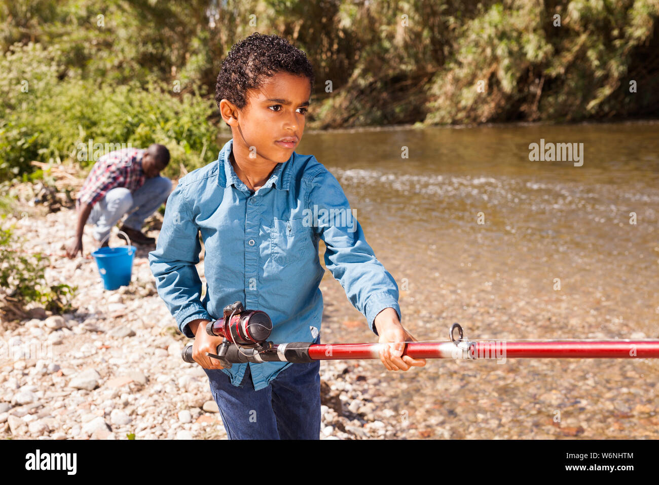 Little African boy fishing with his father and pulling fish Stock Photo