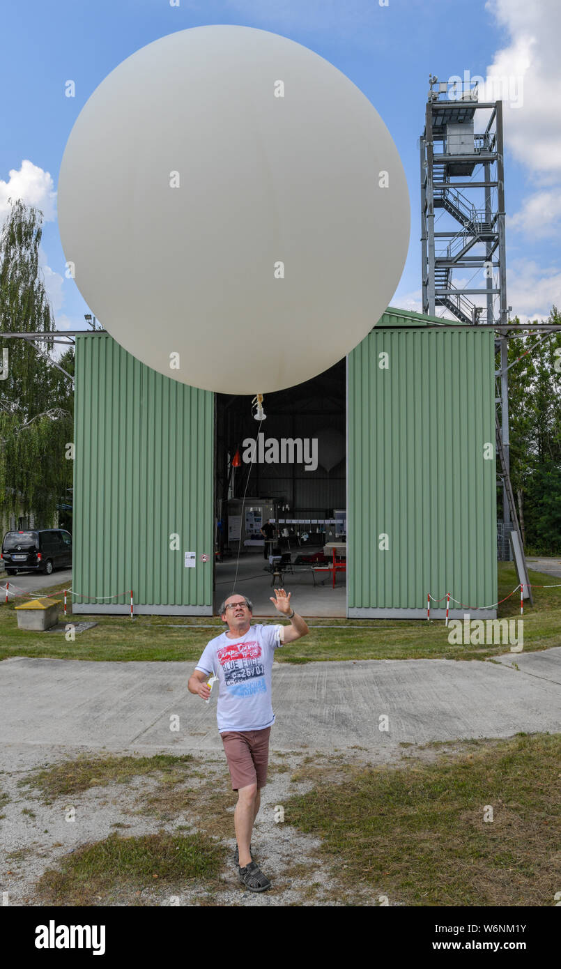 02 August 2019, Brandenburg, Lindenberg: Mario Fellmann, meteorological technician of the Meteorological Observatory Lindenberg - Richard-Aßmann-Observatorium of the German Weather Service (DWD), lets a weather balloon with a radiosonde rise into the sky. One hundred years ago, on 01.08.1919, the high altitude world record for weather kites was established on this site. At that time a weather kite pulled a thin steel cable up to a height of 9750 meters. The record hasn't been broken yet. Germany's first aeronautical warning service was launched in 1911 in this town, about 60 kilometres from Be Stock Photo