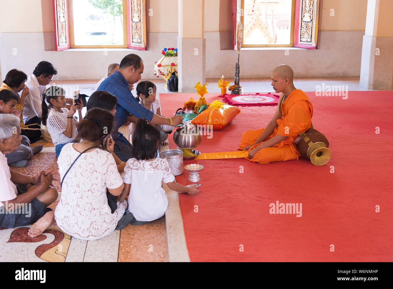 Phuket, Thailand, 04/19/2019 - Single buddhist monk praying with a family  at the Chalong Temple. Stock Photo