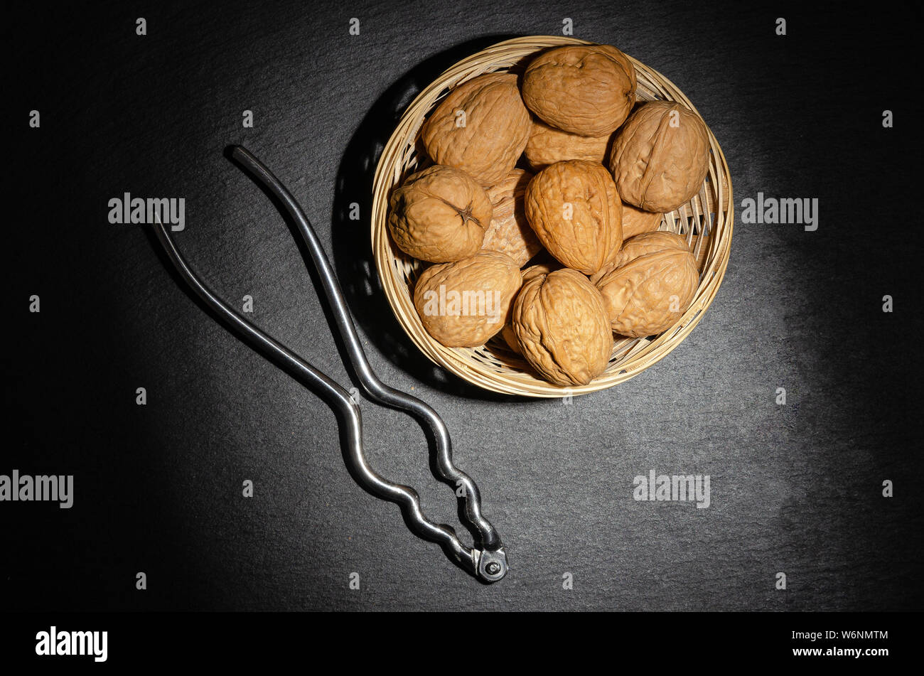 Walnuts with nutcracker on black background, top view. Stock Photo