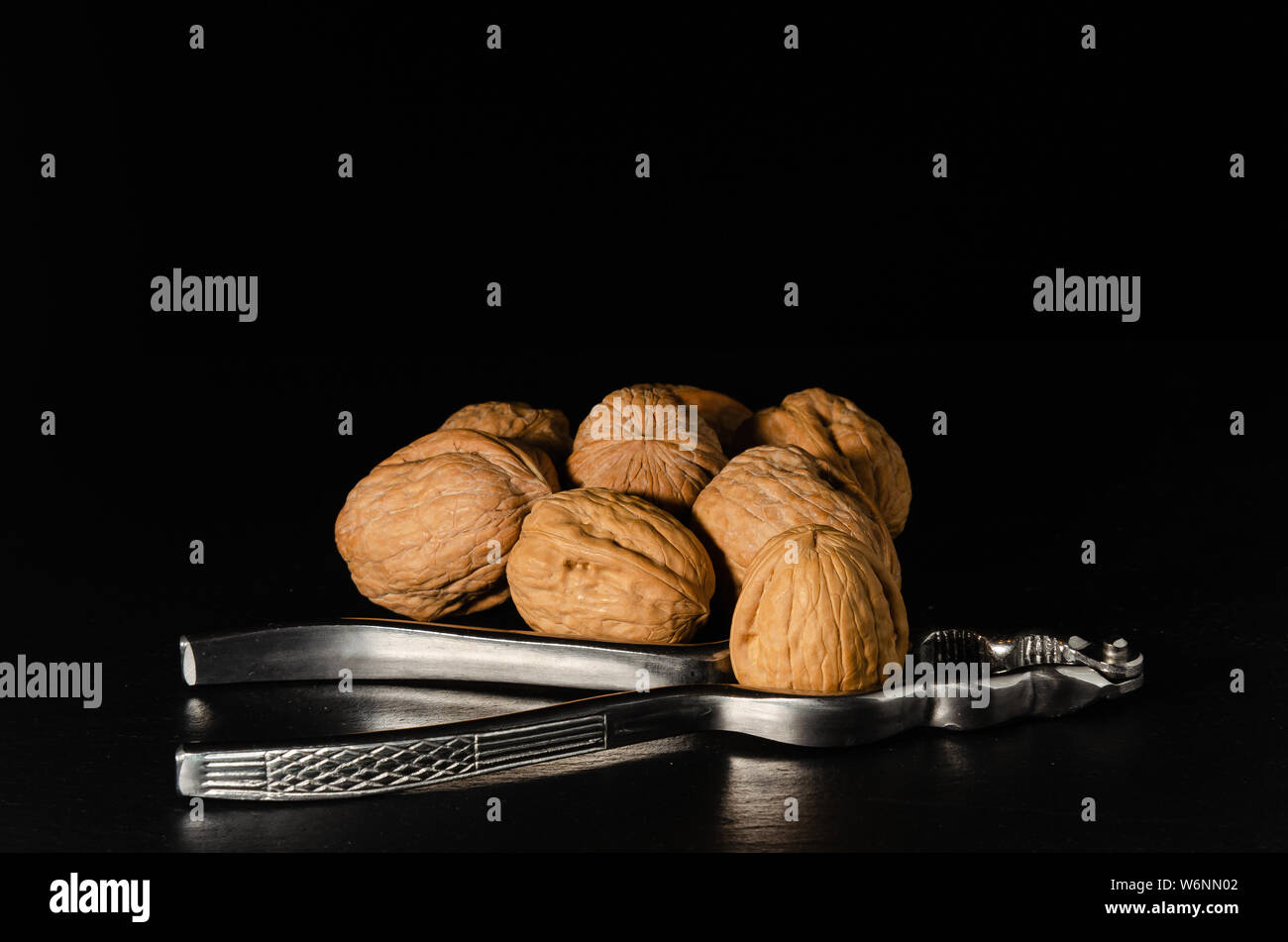 Walnuts with nutcracker over black background. Stock Photo