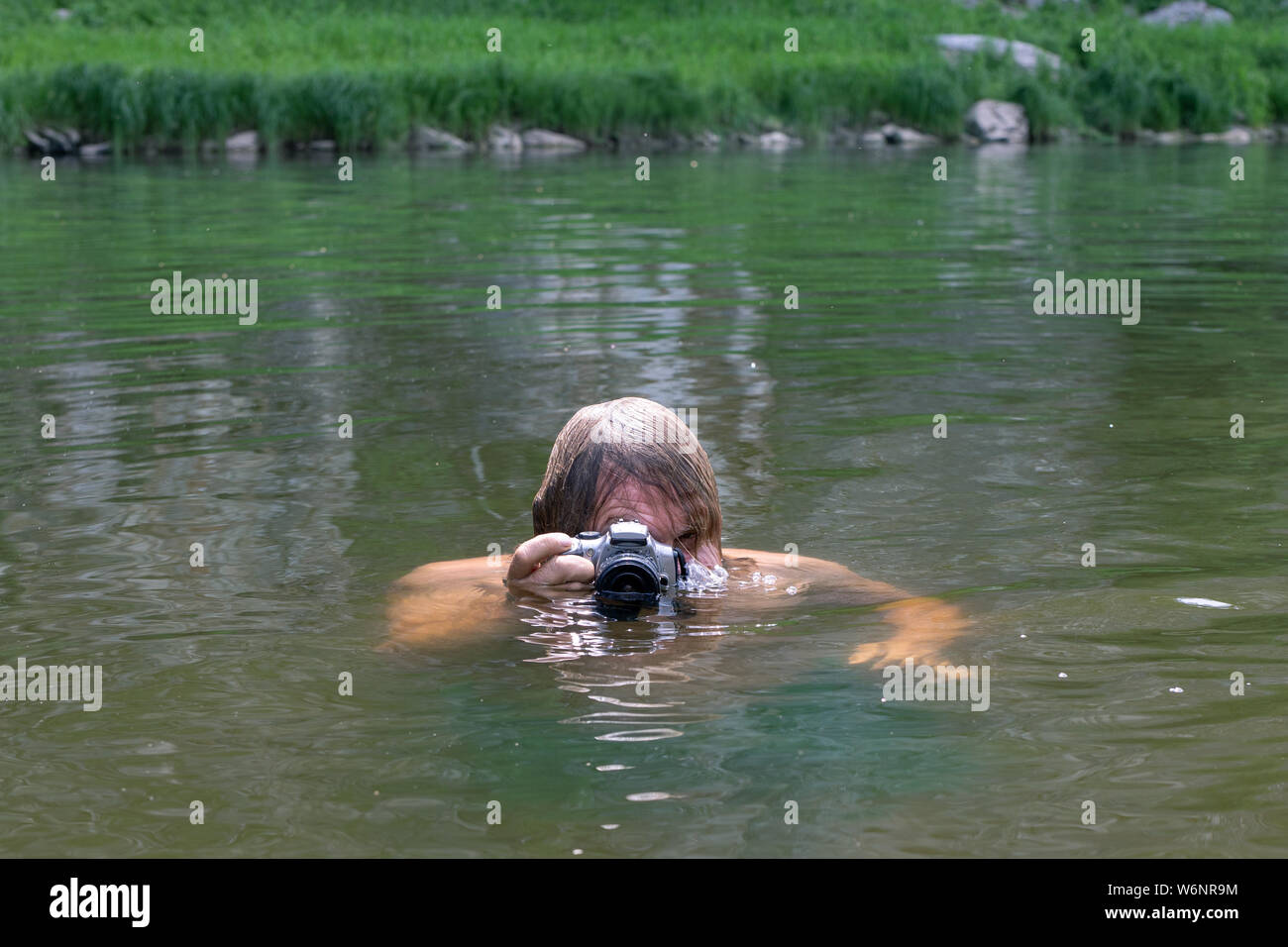 a man aged plunged into the water looking or peeping through a waterproof camera, photographer Stock Photo