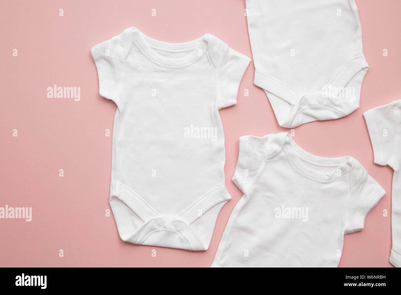 Cute baby white body suit layout on a pastel pink background Stock Photo